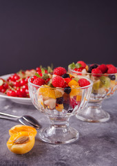salad with fresh fruits and berries on a bowls on the concrete background