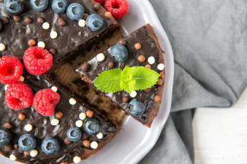 Chocolate cake with chocolate icing, raspberries, blueberries and mint leaves, top view