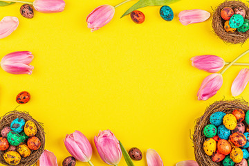 Fototapeta na wymiar Stylish background with colorful easter eggs isolated on yellow background with pink tulip flowers. Flat lay, top view, mockup, overhead, template