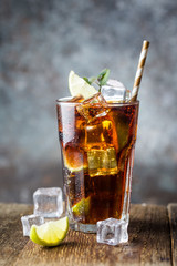 Fresh made Cuba Libre with brown rum, cola, mint and lemon on wooden background