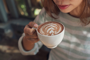 female hand holding cup of hot cocoa or chocolate on wooden table, close up