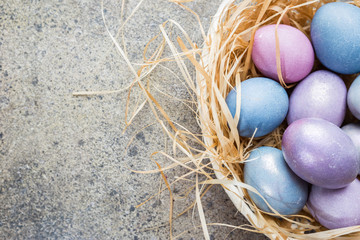 Colorful pastel easter eggs on stone background with space for text, top view.