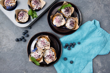 Fototapeta na wymiar Blueberry muffins with white chocolate and fresh blueberries on stone grey table, top view