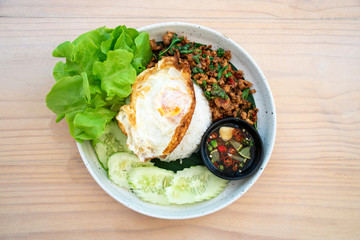 Thai food, rice with stir-fried pork basil on a wooden table