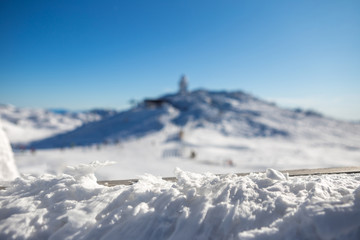 Selective focus on snow on the fence and behind is the ski slopes and ski lifts. It's a beautiful...