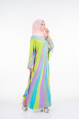 Beautiful female model wearing a pastel batik kaftan/caftan, a traditional dress for Muslim women isolated over white background. Stylish Muslim female hijab fashion lifestyle portraiture concept.