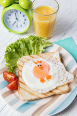Funny toast with fried egg in a shape of chicken and alarm clock, food for kids Easter idea