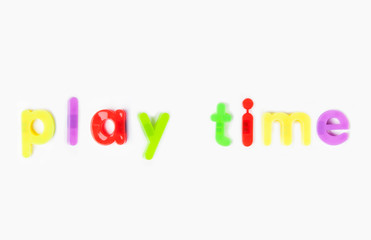 Play time' spelled with alphabet magnets over white background
