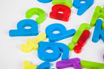Close-up view of alphabet magnets scattered over white background