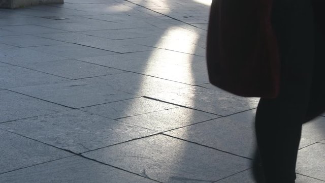 People’s legs and feet are walking in the pedestrian zone gray stone paving in the city