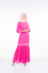 Beautiful female model wearing pink modern kurung, a modern urban lifestyle apparel for Muslim women isolated on white background. Beauty and hijab fashion concept.