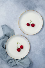 Fresh sweet cherries on two white plate. Top view, background