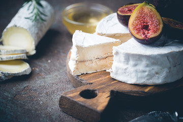 Fresh goat brie cheese with truffle and white mold on cheese platter with figs and honey