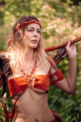 Beautiful girl archer with long blond hair with bow and arrows dressed in leather