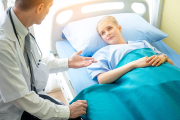 Shot of a doctor meeting with his young female,  Elderly medical expert is having meeting with patient. They are sitting in hospital.