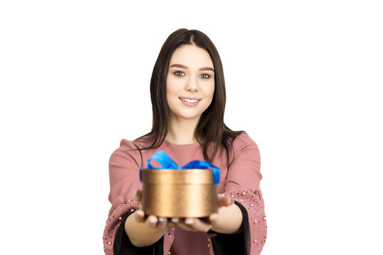 Teenager brunette girl with a gift in her hands on a white background, isolated image The girl accepts a gift from a loved one