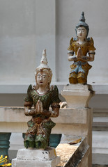 Deva statue in praying hands action decorated on the white concrete railing in thai temple.