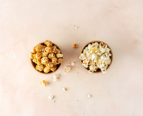 Salted and sweet popcorn in two brown paper buckets on pastel colored background, top view