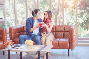 Obraz premium Cheerful couple sharing music on digital tablet in sofa at home
