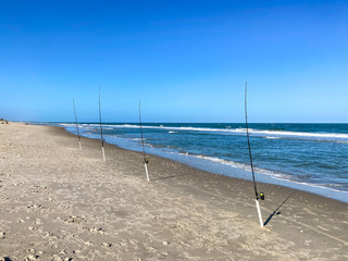 A row of fishing poles with lines cast into the Atlantic Ocean