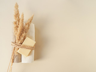 Fototapeta na wymiar Handmade soap, towels and dry plants are tied with a rope on a beige background. Space for text
