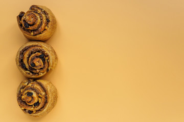 Cinnamon, nut and raisin buns on orange background with copy space