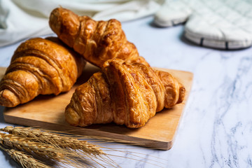 freshly baked croissants on wooden cutting board..
