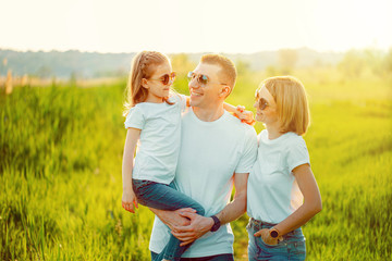 Photo A happy family in white T-shirts, sunglasses and jeans in the park. Summer.