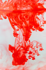 red fluid dropped in a water aquarium drawing some shapes with the gravity