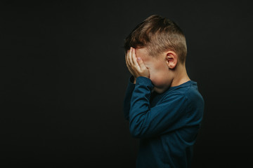 a child whose depression is on a black background with his hands closed