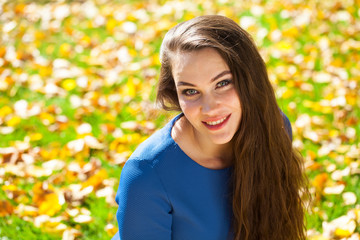 Young beautiful brunette woman in blue dress in autumn park