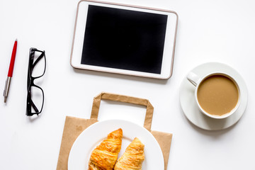 Business lunch with croissant and tablet on white table top view