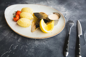 Grilled fish dish on a plate with lemon slice