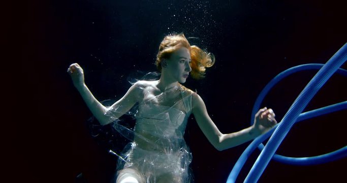 afraid young woman wrapped with plastic waste underwater