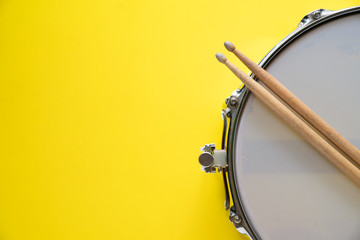 Obraz na płótnie Canvas Drum stick and drum on yellow table background, top view, music concept