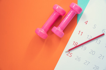 Time for exercising calendar and dumbbell with colorful background on the table