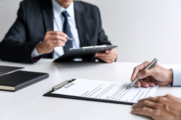 Senior committee manager reading a resume during a job interview, Employer interviewing to ask young male job seeker for recruitment talking in office