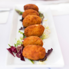 Appetizing meat cutlets fried in flour, 5 pieces, lie on a white long plate on a white table