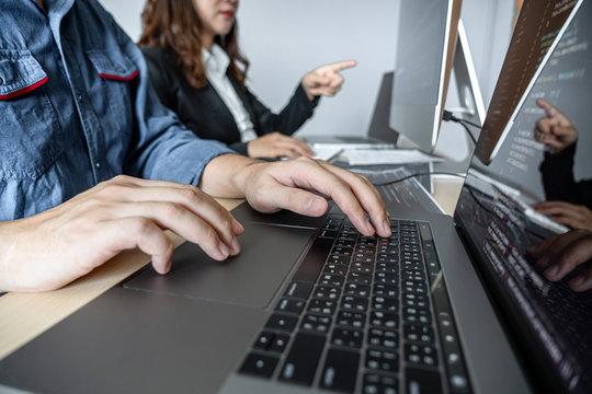 Two professional programmer cooperating and working on web site project in a software developing on desktop computer at company, codes and typing data code, Programming with HTML, PHP and javascript