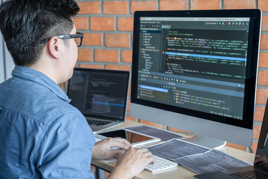 Young Professional programmer working at developing programming and website working in a software develop company office, writing codes and typing data code, Programming with HTML, PHP and javascript