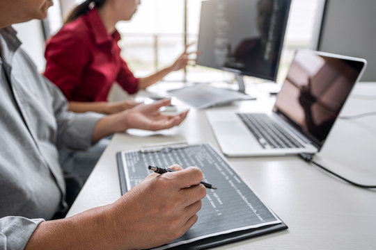 Two professional programmer cooperating and working on web site project in a software developing on desktop computer at company, codes and typing data code, Programming with HTML, PHP and javascript