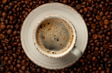 Cup of tasty coffee and beans on a stone background. 