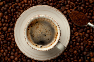 Cup of tasty coffee and beans on a stone background. 