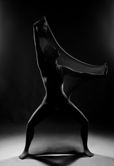 Slim girl wearing a white bodysuit dances a modern avant garde dance, covering her body with...
