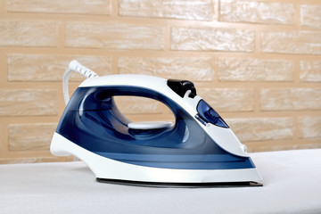 New modern electric steam iron on ironing board