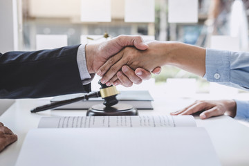 Handshake after good cooperation, Businesswoman Shaking hands with Professional male lawyer after discussing good deal of contract in courtroom, Concepts of law, Judge gavel with scales of justice