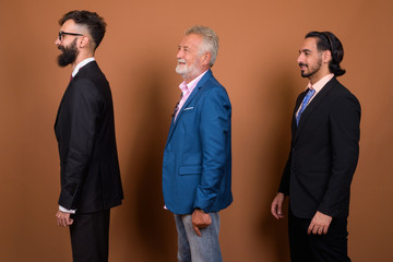 Three multi ethnic bearded businessmen together against brown background