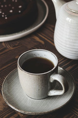Moist Ginger Chocolate cake sprinkled with sea salt, cup of tea and teapot on wooden table. Selective focus. Haze effect