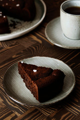 Moist Ginger Chocolate cake sliced and sprinkled with sea salt and cup of tea on wooden table. Selective focus.