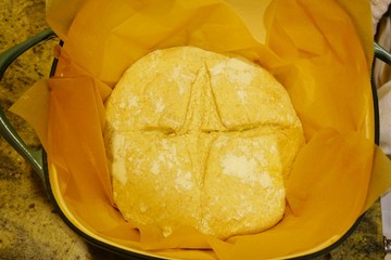Placing a ball of slashed proofed yeast dough for miracle overnight no knead bread in a Dutch oven